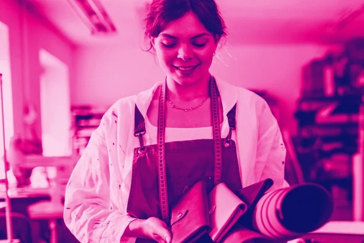Una emprendedora en su taller de cuero, sonriendo, con una pieza en las manos